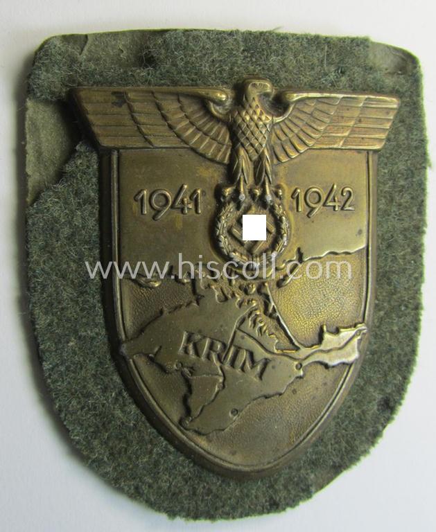 Attractive, WH (Heeres o. Waffen-SS) 'Krim'-campaign-shield that comes mounted onto its original, field-grey-coloured 'backing' and that comes in an issued-, minimally worn and/or (I deem) carefully tunic-removed-, condition