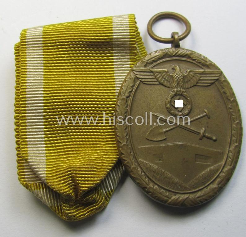 Medal-set: 'Deutsches Schutzwall Ehrenzeichen' (aka: 'Westwall'-medal) being a non-maker-marked- and/or: 'Buntmetall'-based specimen that comes together with its period- (and neatly folded ie. pre-confectioned) ribbon (ie. 'Bandabschnitt')