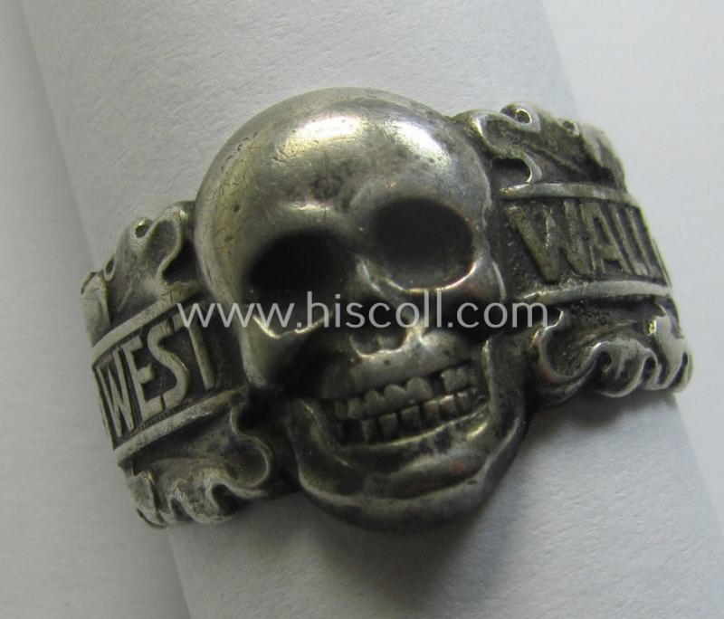 Attractive - very desirable and scarcely found! - Third-Reich-period, metal-based (ie. shiny silver-coloured- and I deem genuine silver-based) so-called: 'souvenir'-ring depicting a detailed skull (ie. 'Totenkopf') coupled with the text: 'Westwall'