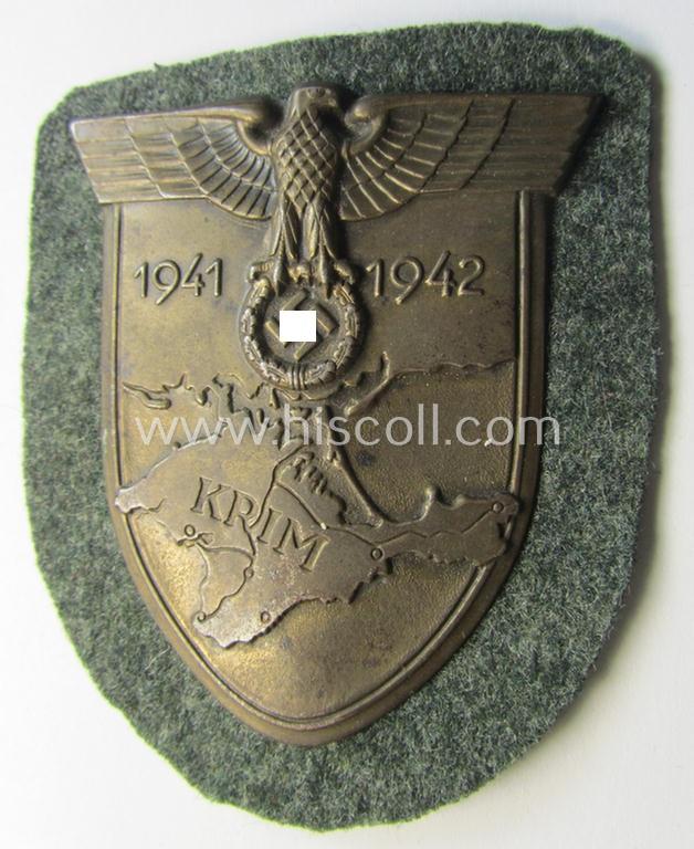 Attractive, WH (Heeres o. Waffen-SS) 'Krim'-campaign-shield that comes mounted onto its original, field-grey-coloured 'backing' and that comes in an issued-, minimally worn and/or (I deem) carefully tunic-removed-, condition