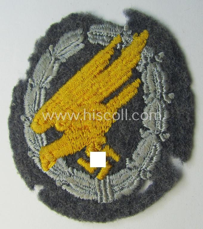 WH (Luftwaffe) 'Fallschirmschützen-Abzeichen in Stoff' (or: cloth-based paratroopers'-jump-badge) being a nicely machine-embroidered specimen that comes in a probably issued albeit (I deem) never used- ie. 'virtually mint', condition