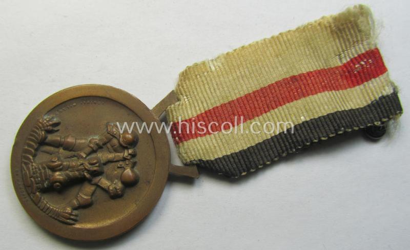 Attractive, golden-bronze-coloured- (and I deem 'Buntmetall'-based-) example of a: 'Deutsch-Italienische Feldzugsmedaille' (or: German-Italian campaign-medal) that comes mounted onto its (regular-sized) piece of original (albeit truly faded) ribbon