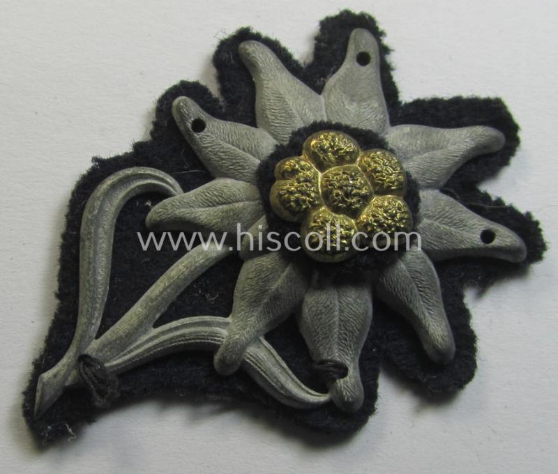 Unusual WH (Heeres or Waffen-SS) silver-greyish-coloured, zinc-based and 'woolen backed' so-called: M43-cap-badge (ie. 'Mützenabzeichen') depicting an: 'Edelweiss'-flower as was used by the various 'Gebirgsjäger'-related divisional-staff