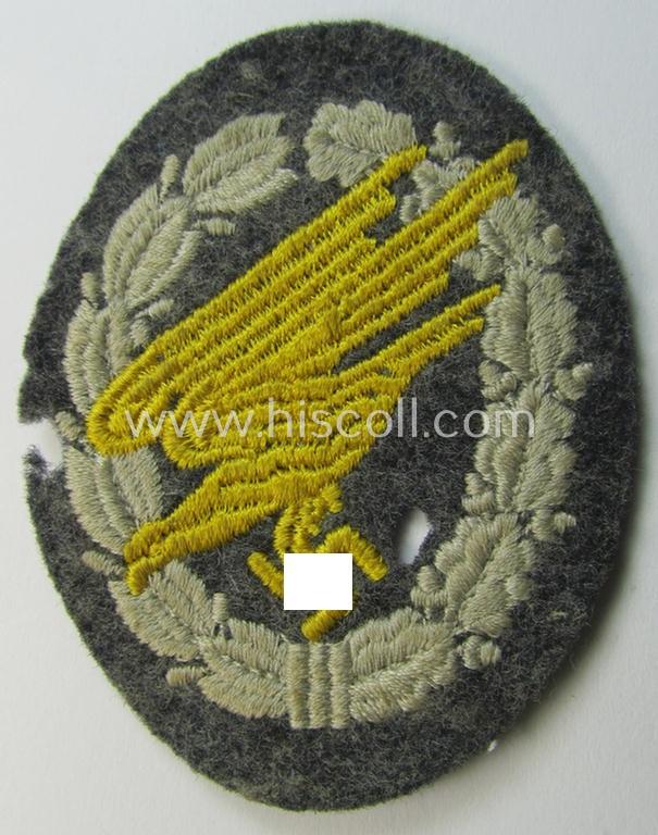 WH (Luftwaffe) 'Fallschirmschützen-Abzeichen in Stoff' (or: cloth-based paratroopers'-jump-badge) being a nicely machine-embroidered specimen that comes in a probably issued albeit (I deem) never used- ie. 'virtually mint', condition