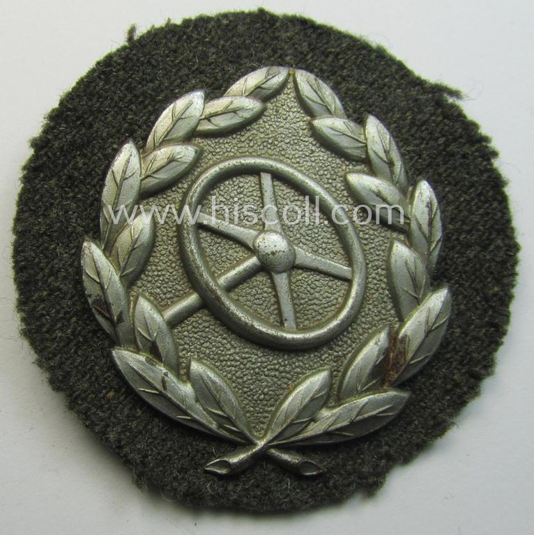 Moderately worn, WH (Heeres- ie. Waffen-SS) so-called: 'Kraftfahrbewährungs-Abzeichen in Silber' (or: silver-class drivers' proficiency-badge) that comes mounted onto its piece of field-grey-coloured wool