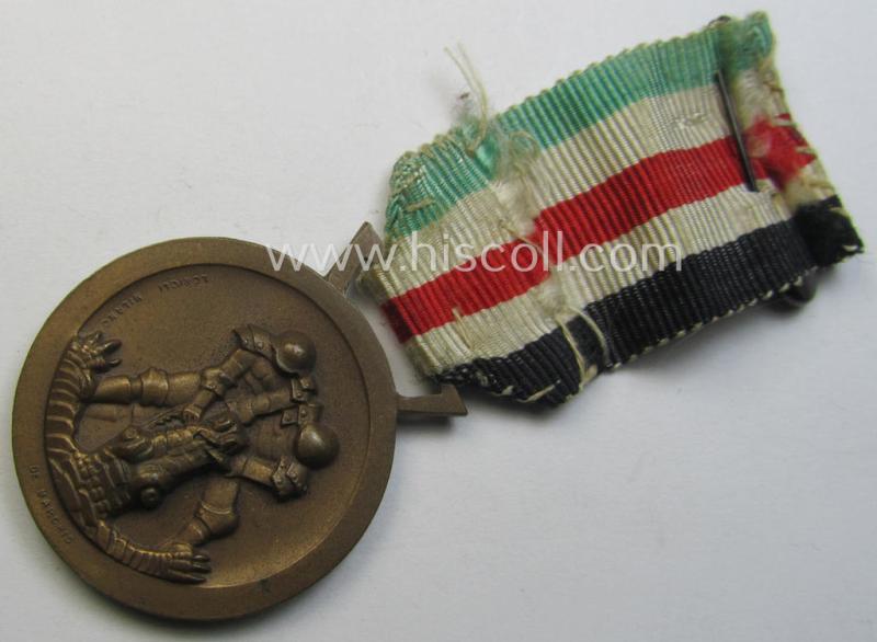 Attractive, golden-bronze-coloured- (and I deem 'Buntmetall'-based-) example of a: 'Deutsch-Italienische Feldzugsmedaille' (or: German-Italian campaign-medal) that comes mounted onto its (regular-sized) piece of original (an minimally faded) ribbon