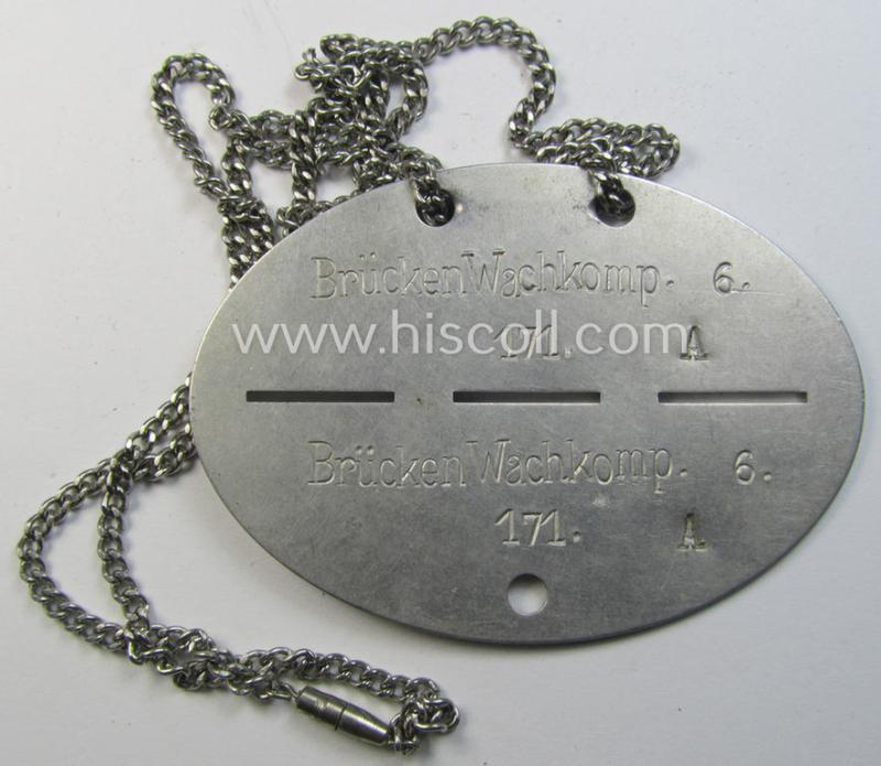 Unusual - and scarcely found! - aluminium-based, WH (Heeres) related ID-disc (ie. 'Erkennungsmarke') bearing the stamped unit-designation that reads: 'Brücken Wachkomp. 6.' and that comes mounted onto its period, metal-based 'chain'