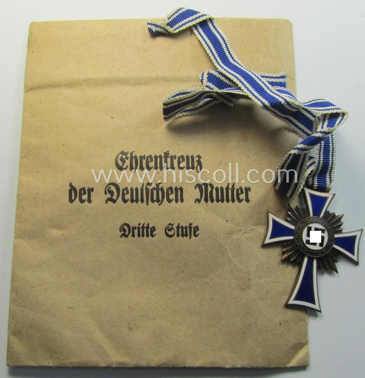 Attractive, 'Ehrenkreuz der deutschen Mutter - dritte Stufe' (or: bronze-class mothers'-cross) that came mounted onto its long-sized ribbon and that came stored in its period pouch (by the unusually seen maker: 'Wilhelm A. Jäger - Frankfurt a.M.')