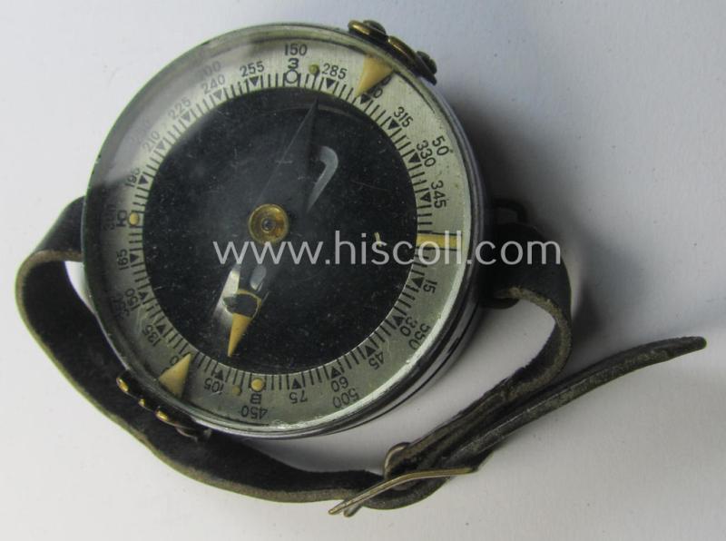 Russian WWII-period, 'standard-issue'-pattern compass (or: 'Marschkompass') as executed in 'Bakelite' being a used example that shows a clearly present date (1941) and makers'-designation and that comes mounted onto its period leather-based strap