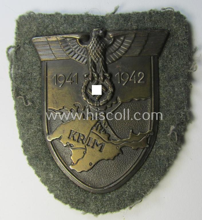 Attractive, WH (Heeres o. Waffen-SS) 'Krim'-campaign-shield that comes mounted onto its original, field-grey-coloured 'backing' and that comes in a surely issued-, minimally worn and/or (I deem) carefully tunic-removed-, condition