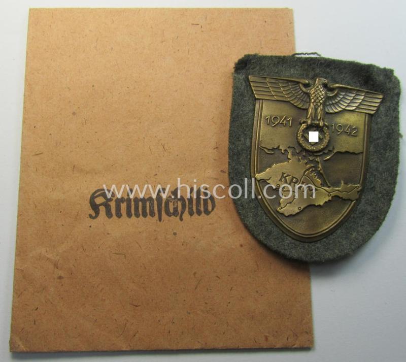 Superb, WH (Heeres ie. Waffen-SS) 'Krim'-campaign-shield (by the maker: 'Friedrich Orth') that comes stored in its period (and rarely seen!) 'Zellstoff'-based pouch and that comes in a probably issued- (albeit still 'virtually mint'-), condition