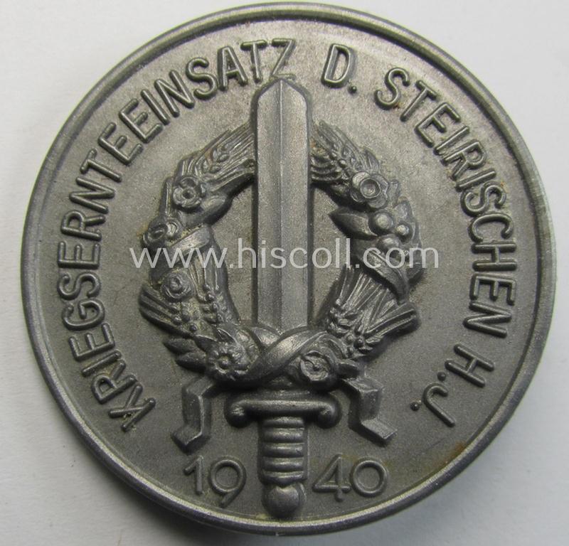 Commemorative - silverish-grey-coloured and unusually resin-based(!) -'HJ'-related 'tinnie' being a non-maker-marked example depicting an upright-postioned sword and wreath surrounded by the text: 'Kriegsernteeinsatz d. Steierischen-HJ - 1940'