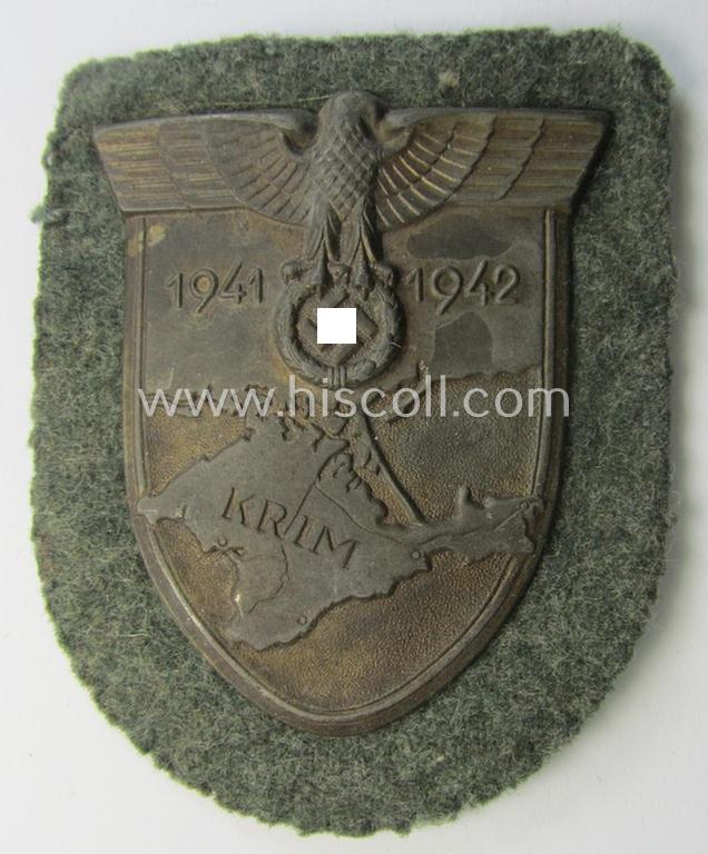 Attractive, WH (Heeres o. Waffen-SS) 'Krim'-campaign-shield that comes mounted onto its original, field-grey-coloured 'backing' and that comes in a surely issued-, minimally worn and/or (I deem) carefully tunic-removed-, condition