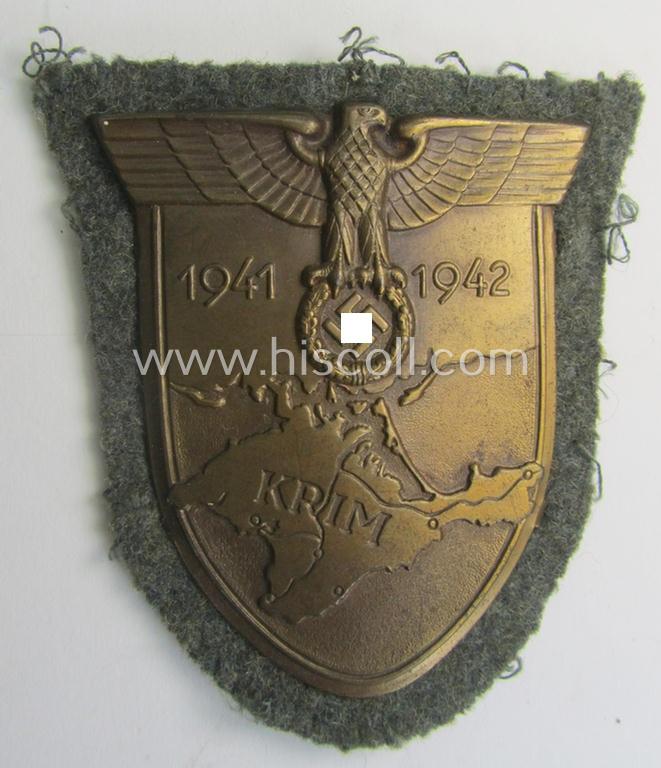 Attractive, WH (Heeres o. Waffen-SS) 'Krim'-campaign-shield that comes mounted onto its original, field-grey-coloured 'backing' and that comes in a surely issued-, minimally worn and/or (I deem) carefully tunic-removed-, condition