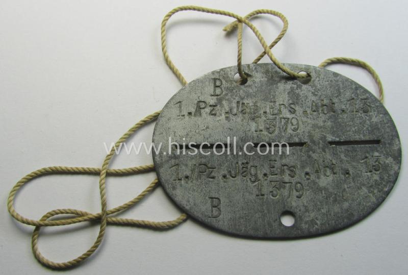 Attractive, zinc-based WH (Heeres) (ie. 'Pz-Jäger'-related) ID-disc bearing the clearly stamped unit-designation that reads: '1./Pz.Jäg.Ers.Abt. 13' and that comes still mounted onto its (period-attached) cord as issued- and/or worn