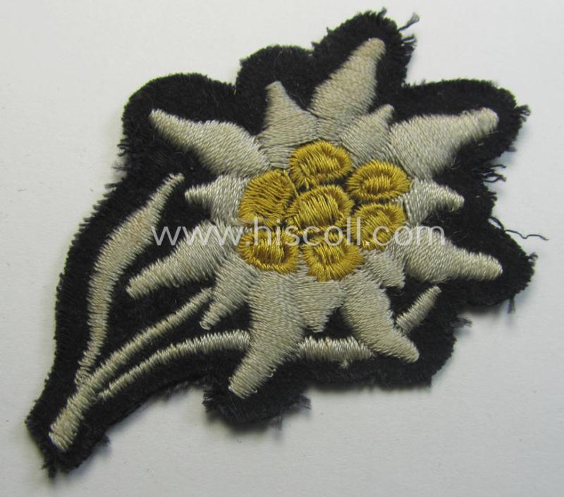 Neat - and I deem truly used and/or worn! - Waffen-SS-pattern, black-coloured M43-cap-insignia (ie. 'Mützenabzeichen') depicting an: 'Edelweiss'-flower as used by the various 'Gebirgsjäger'- (ie. mountain-troops-) related divisional-staff