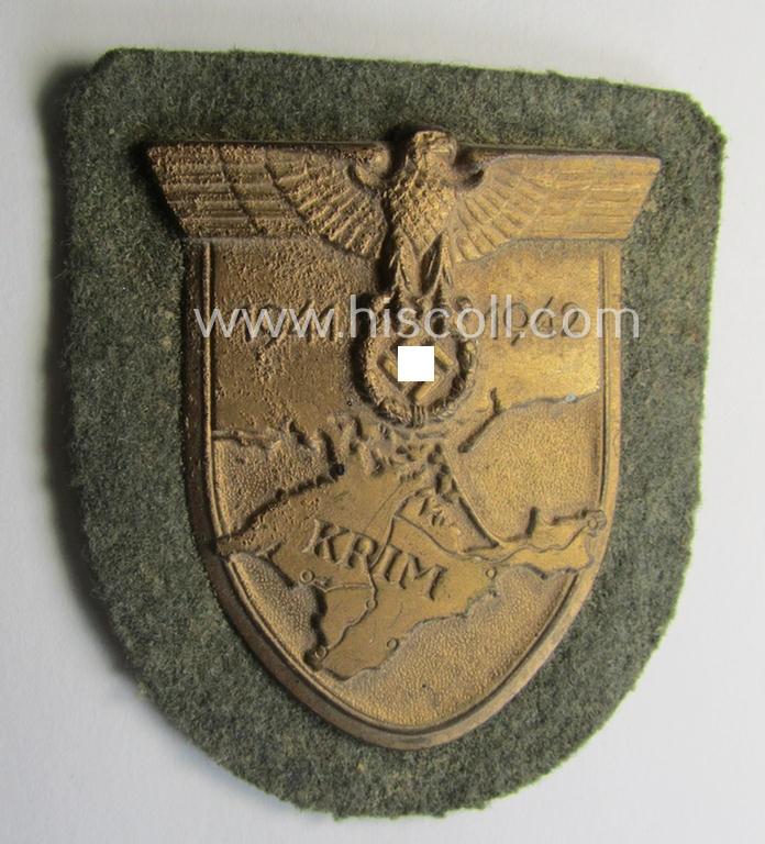 Attractive, WH (Heeres o. Waffen-SS) 'Krim'-campaign-shield that comes mounted onto its original, field-grey-coloured 'backing' and that comes in a surely issued-, minimally worn and/or (I deem) carefully tunic-removed-, condition