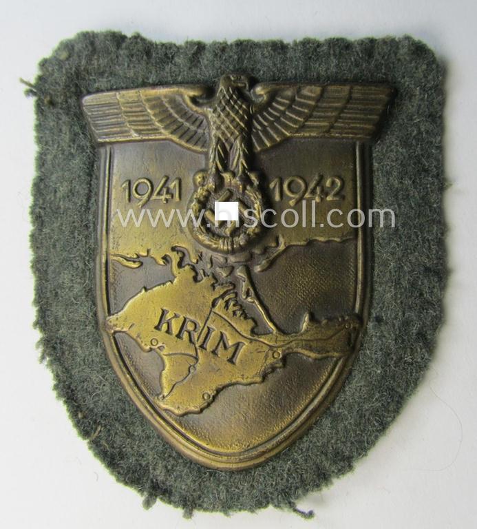 Attractive - truly worn! - WH (Heeres o. Waffen-SS) 'Krim'-campaign-shield that comes mounted onto its original, field-grey-coloured 'backing' and that comes in a surely issued-, worn and/or carefully tunic-removed-, condition