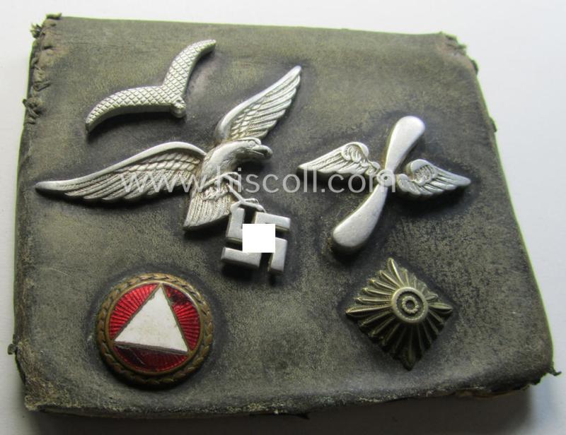 Unusual, WH (Luftwaffe) item that comes as a 'period-souvenir': a part of a leather-based 'wallet' that holds various LW-insignia (such as a visor-cap-eagle, single pip, 'Schwinge' and a: - presumed - LW-'Traditions-Abz.')