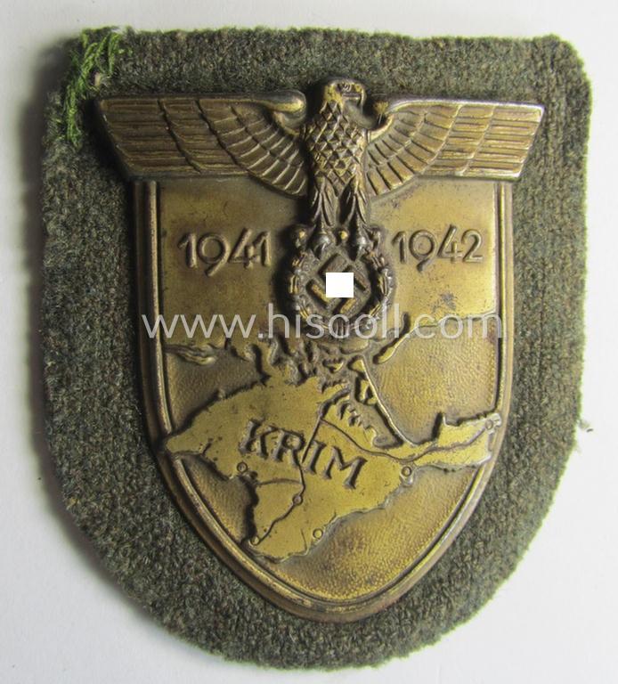 Attractive - truly worn! - WH (Heeres o. Waffen-SS) 'Krim'-campaign-shield that comes mounted onto its original, field-grey-coloured 'backing' and that comes in a surely issued-, worn and/or carefully tunic-removed-, condition