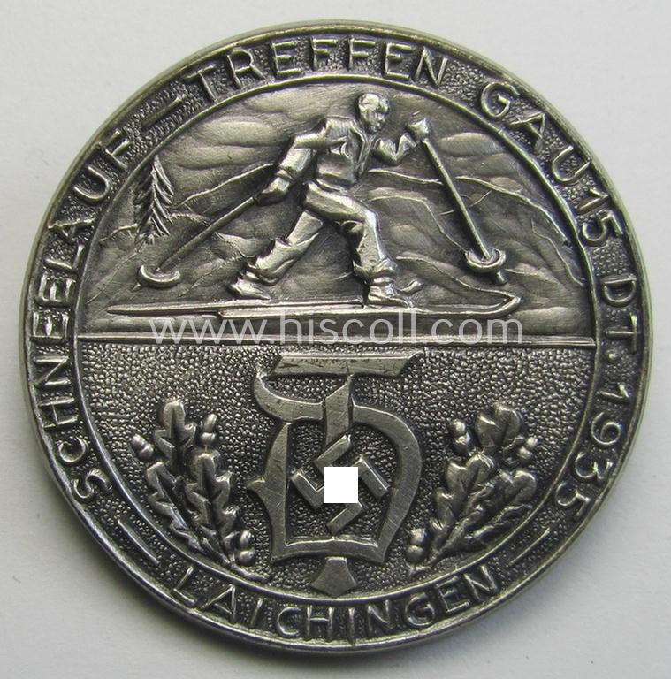 Unusual, 'Deutscher Turnerbund'-related 'tinnie' being a non-maker-marked example depicting a person on ski’s, the: 'Deutscher Turnerbund'-logo and text that reads: 'Schneelauf-Treffen - Gau 15 D.T. 1935 - Laichingen'