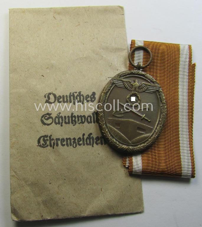 Medal-set: 'Deutsches Schutzwall Ehrenzeichen' (aka: 'Westwall'-medal) being a non-maker-marked- and/or: typical 'Buntmetall'-based specimen that comes packed in its original pouch of issue by the: 'Carl Poellath'-company